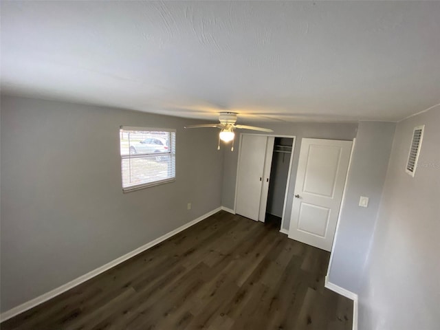 unfurnished bedroom featuring a closet, visible vents, dark wood-type flooring, ceiling fan, and baseboards