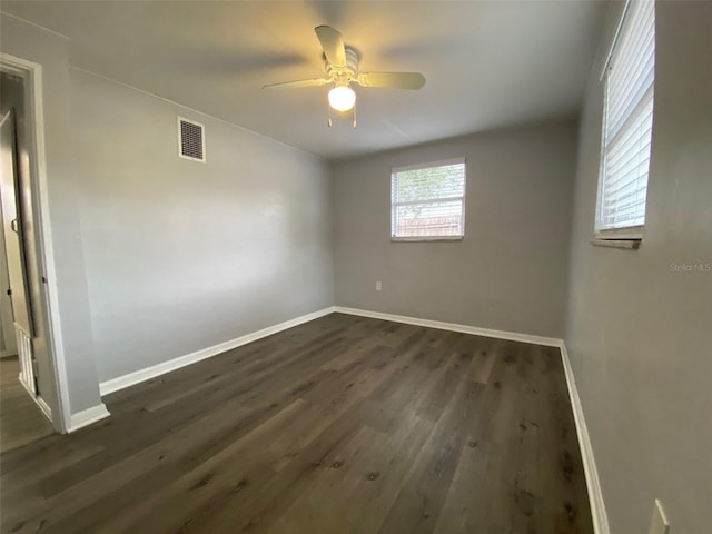 empty room with a ceiling fan, baseboards, visible vents, and dark wood-style flooring