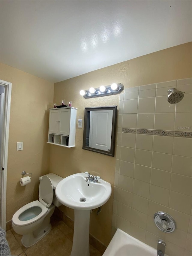 full bath with washtub / shower combination, tile patterned flooring, and toilet