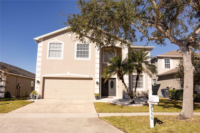 view of front of house featuring an attached garage, a front yard, concrete driveway, and stucco siding