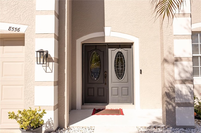 doorway to property with a garage and stucco siding