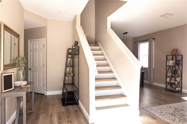 stairway featuring visible vents, baseboards, and wood finished floors