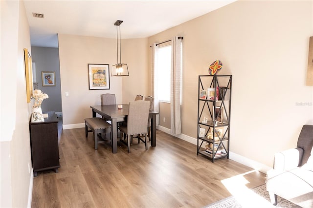 dining room with light wood-style flooring, visible vents, and baseboards