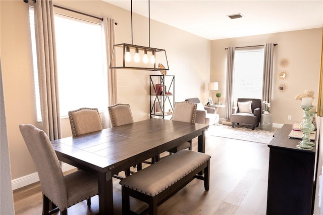 dining room with visible vents, light wood-style flooring, and baseboards