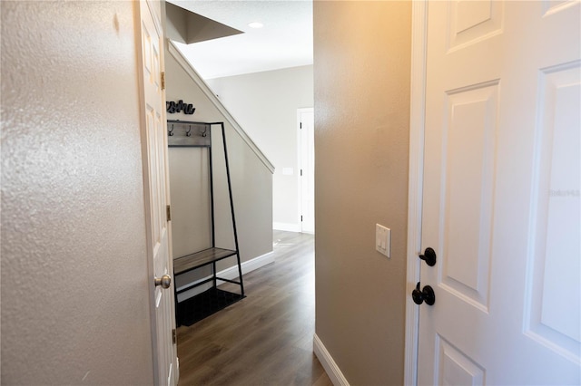 corridor featuring dark wood-type flooring and baseboards