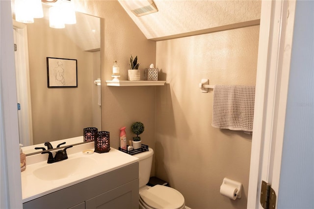 bathroom with visible vents, a textured wall, vanity, and toilet