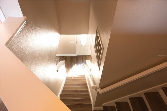 staircase featuring a textured wall and wood finished floors