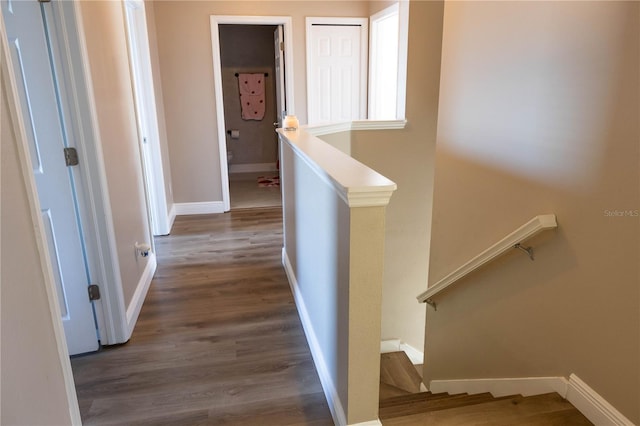 corridor featuring baseboards, an upstairs landing, and wood finished floors