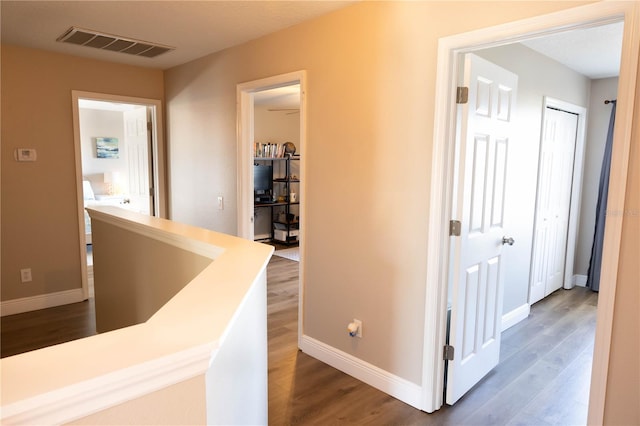 corridor featuring dark wood-style floors, visible vents, and baseboards