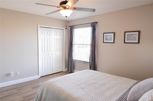 bedroom with light wood finished floors, ceiling fan, baseboards, and a closet