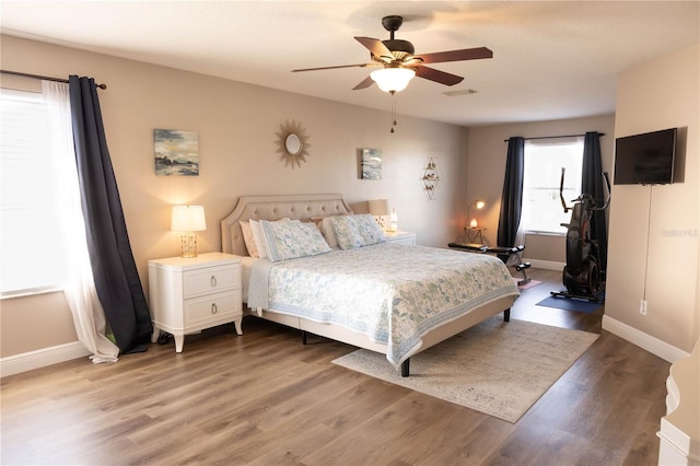 bedroom featuring ceiling fan, visible vents, baseboards, and wood finished floors