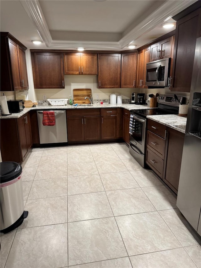 kitchen with light tile patterned floors, stainless steel appliances, a tray ceiling, and light stone counters