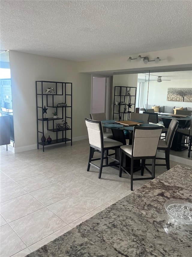 tiled dining area with a textured ceiling and baseboards