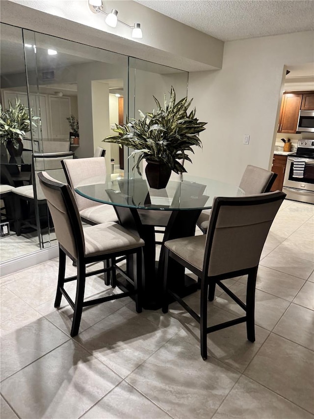 dining space with a textured ceiling and light tile patterned floors