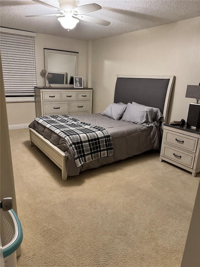 bedroom featuring a textured ceiling, a ceiling fan, and light colored carpet