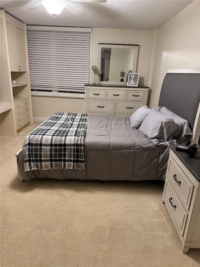 bedroom featuring light carpet, a ceiling fan, and a textured ceiling