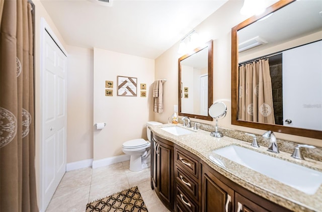 bathroom with tile patterned flooring, a sink, toilet, and double vanity