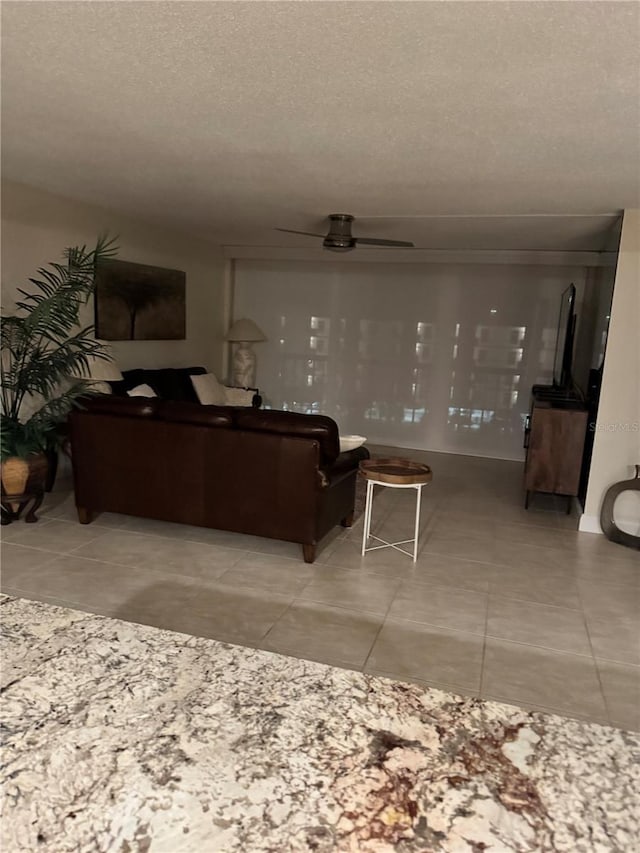 living room featuring ceiling fan, a textured ceiling, and tile patterned floors