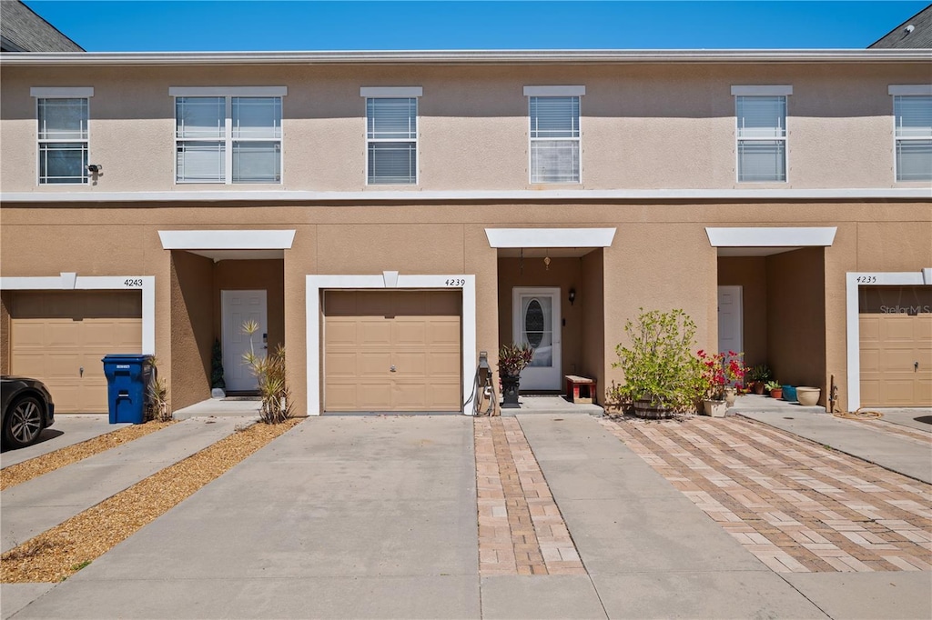 view of property with driveway, an attached garage, and stucco siding