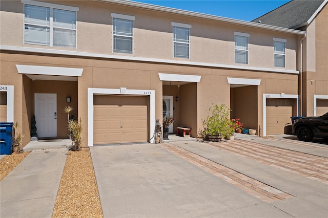 multi unit property with a garage, driveway, and stucco siding