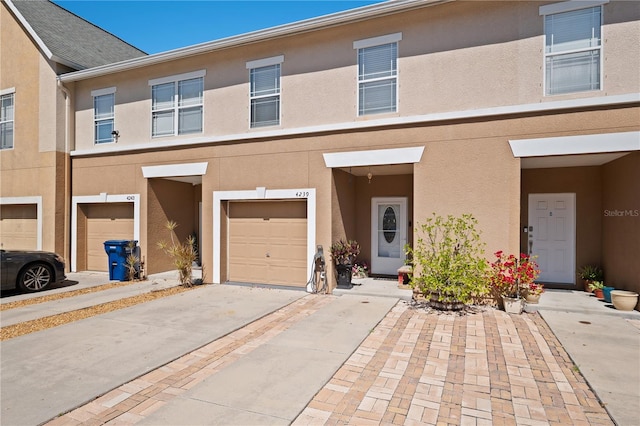 multi unit property featuring driveway, an attached garage, and stucco siding