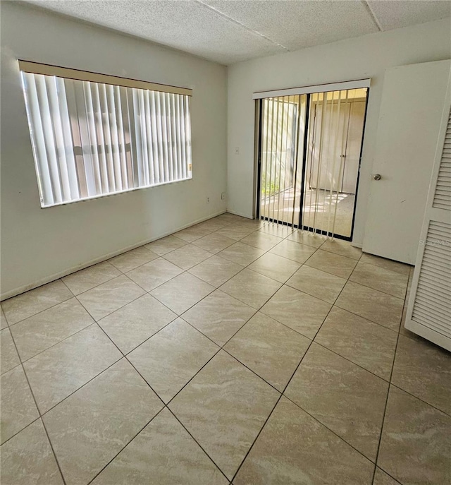 tiled empty room with plenty of natural light and a textured ceiling