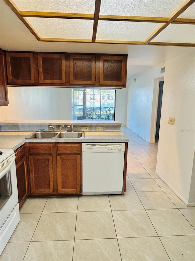 kitchen featuring a sink, white appliances, light countertops, and light tile patterned floors