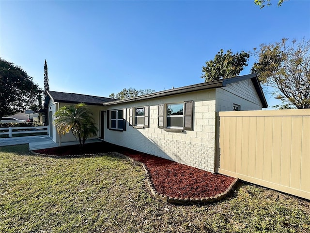 view of side of property featuring a lawn and concrete block siding