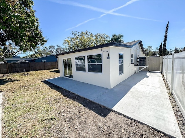 rear view of house featuring a patio, a fenced backyard, a gate, and stucco siding