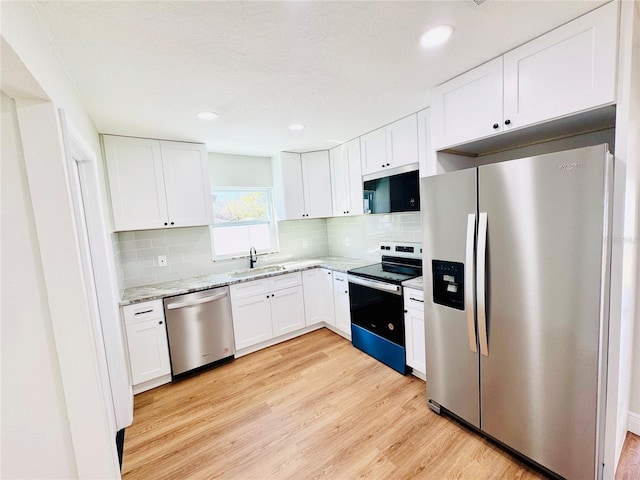 kitchen with appliances with stainless steel finishes, light wood-type flooring, a sink, and white cabinets