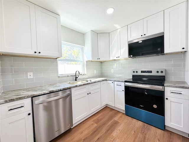 kitchen with range with electric cooktop, dishwasher, light wood-style floors, black microwave, and a sink