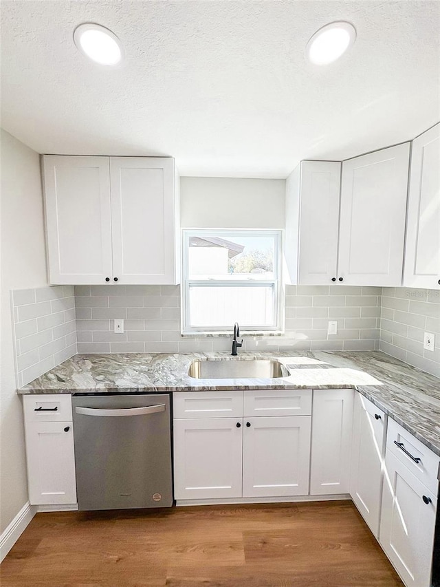 kitchen with a sink, light wood-style flooring, white cabinets, and dishwasher