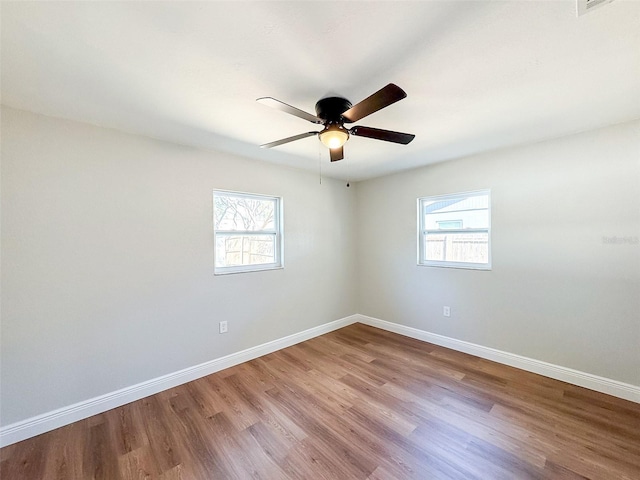 empty room featuring ceiling fan, wood finished floors, visible vents, and baseboards