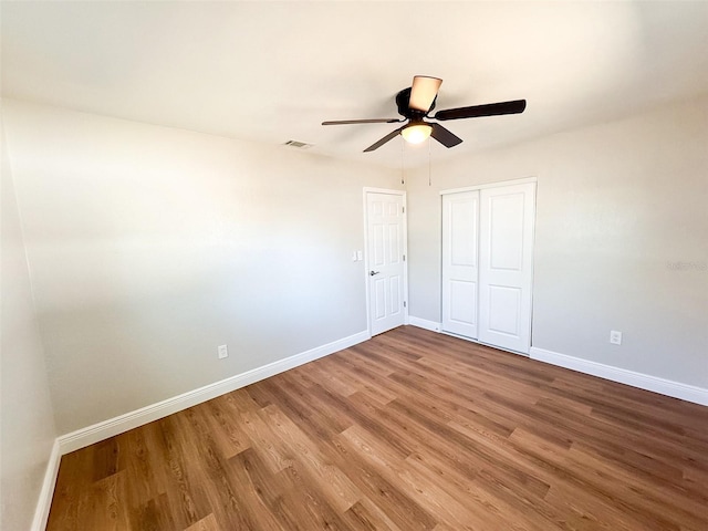 unfurnished bedroom with baseboards, visible vents, ceiling fan, wood finished floors, and a closet