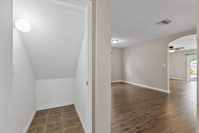 interior space with baseboards, visible vents, arched walkways, wood finished floors, and a textured ceiling