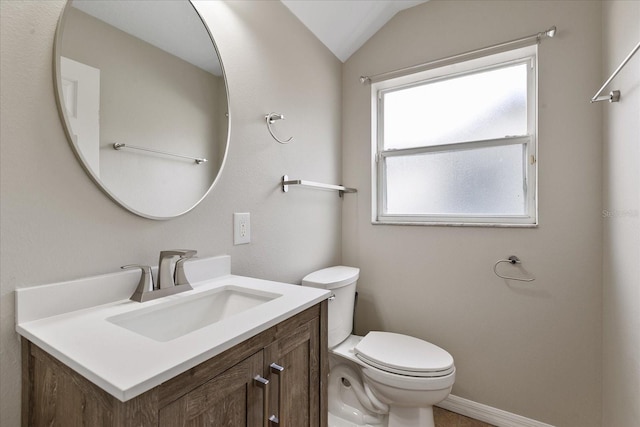 half bathroom featuring lofted ceiling, baseboards, vanity, and toilet