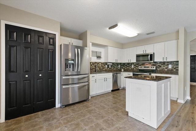 kitchen with visible vents, decorative backsplash, appliances with stainless steel finishes, white cabinetry, and a sink