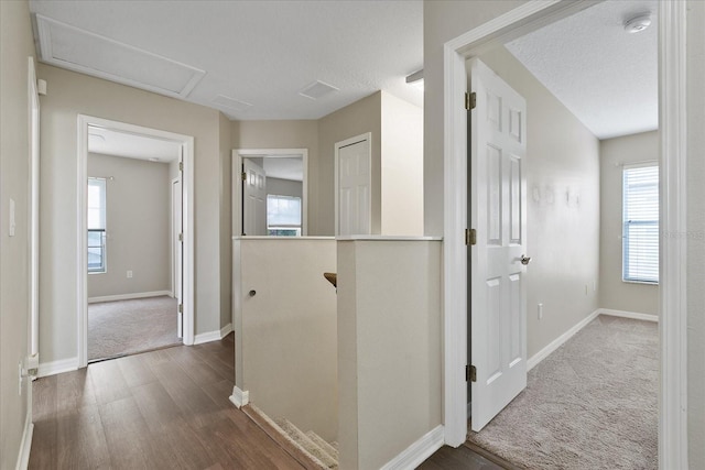 hallway featuring baseboards, carpet flooring, wood finished floors, and an upstairs landing