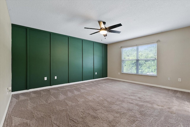 carpeted spare room featuring ceiling fan, a textured ceiling, and baseboards