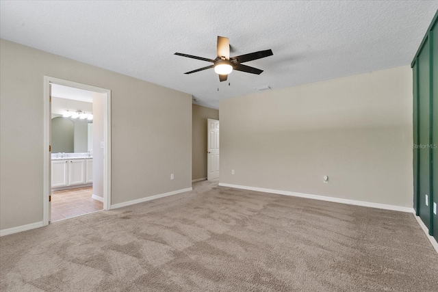 spare room with a textured ceiling, baseboards, a ceiling fan, and light colored carpet