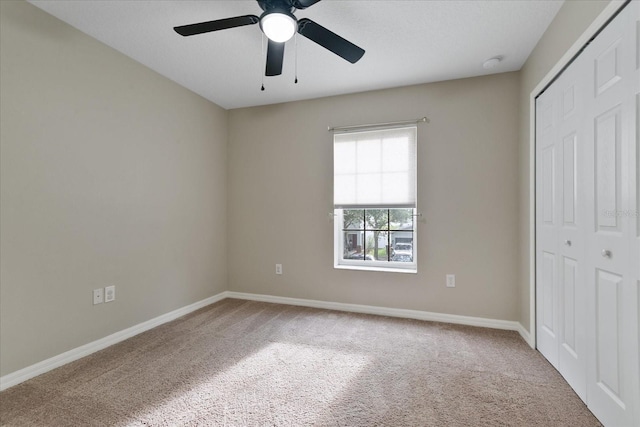 unfurnished bedroom with a ceiling fan, carpet, a closet, and baseboards