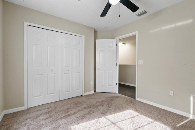 unfurnished bedroom featuring baseboards, visible vents, ceiling fan, carpet, and a closet