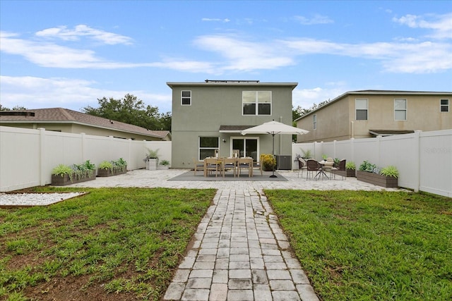 rear view of house featuring a yard, a fenced backyard, and a patio