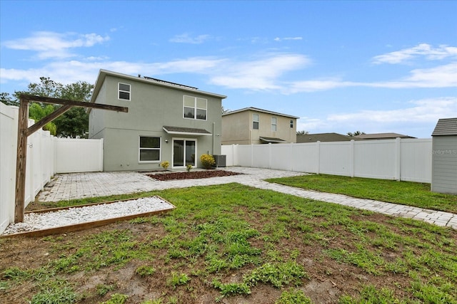 back of house featuring a patio, a fenced backyard, a yard, central air condition unit, and stucco siding