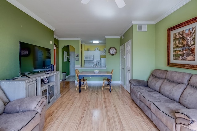 living room with baseboards, visible vents, crown molding, and light wood finished floors