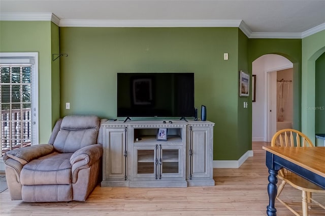 living area featuring light wood-style floors, arched walkways, ornamental molding, and baseboards