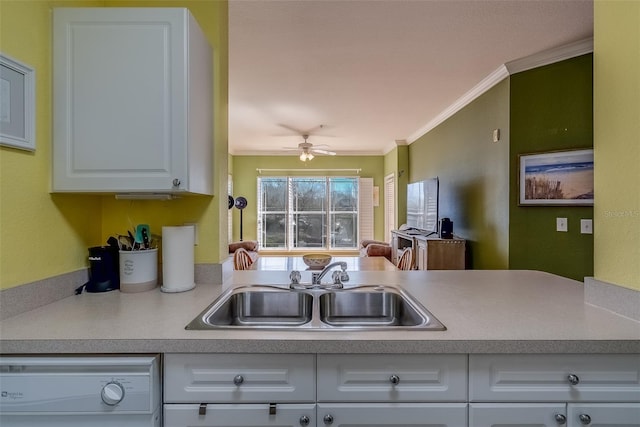 kitchen with white dishwasher, a sink, a ceiling fan, white cabinets, and ornamental molding