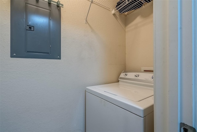 laundry area featuring washer / dryer, electric panel, and a textured wall