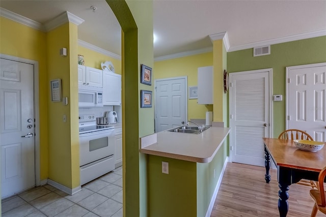 kitchen featuring visible vents, white cabinetry, a sink, white appliances, and a peninsula