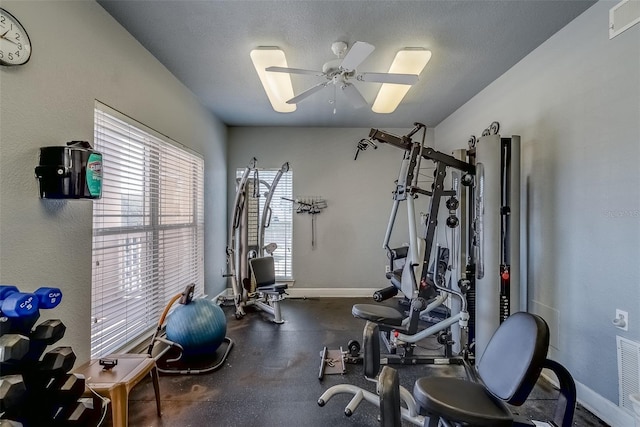 exercise room with ceiling fan, visible vents, baseboards, and a textured ceiling